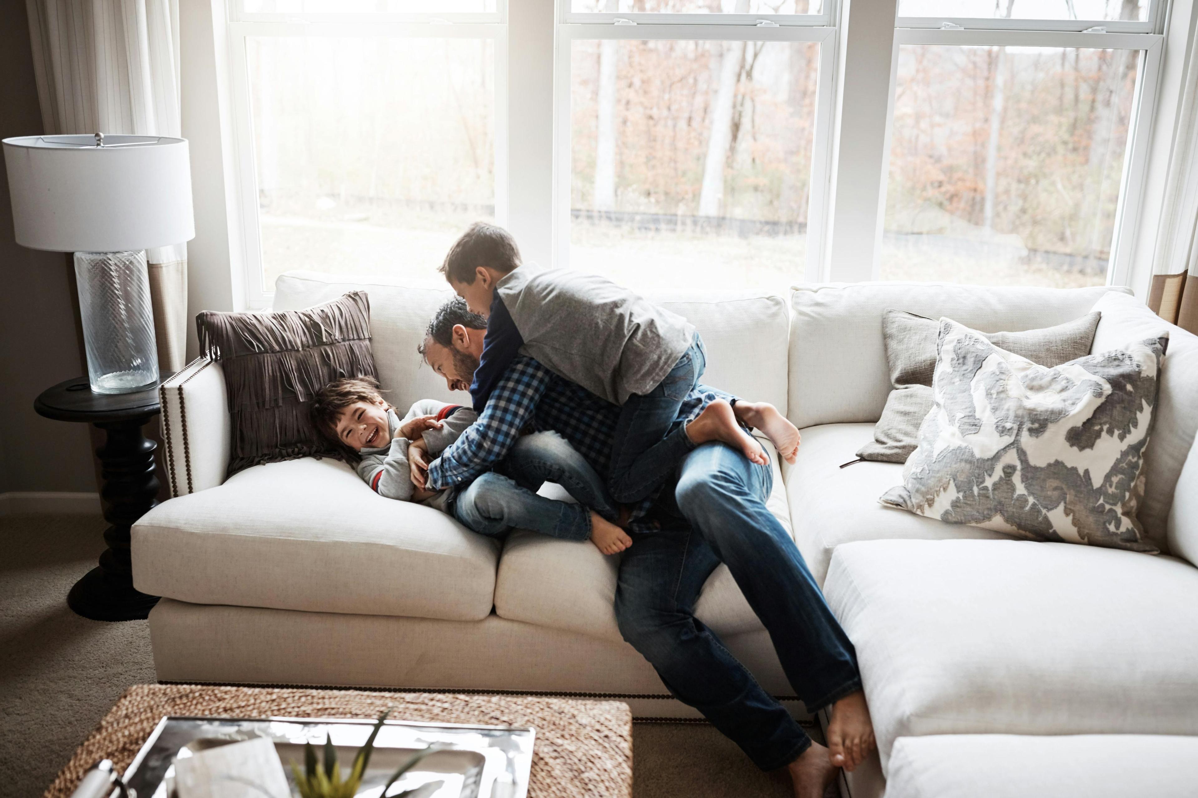 dad and sons playing on a sofa